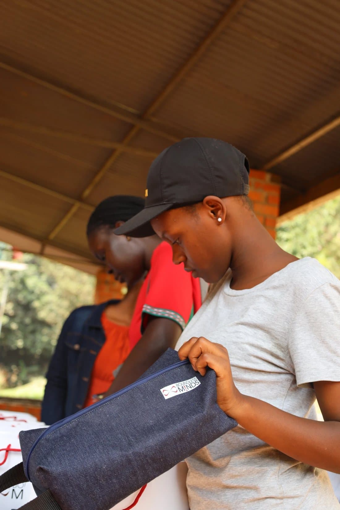 A Corps member checking a denim pencil bag at a stall